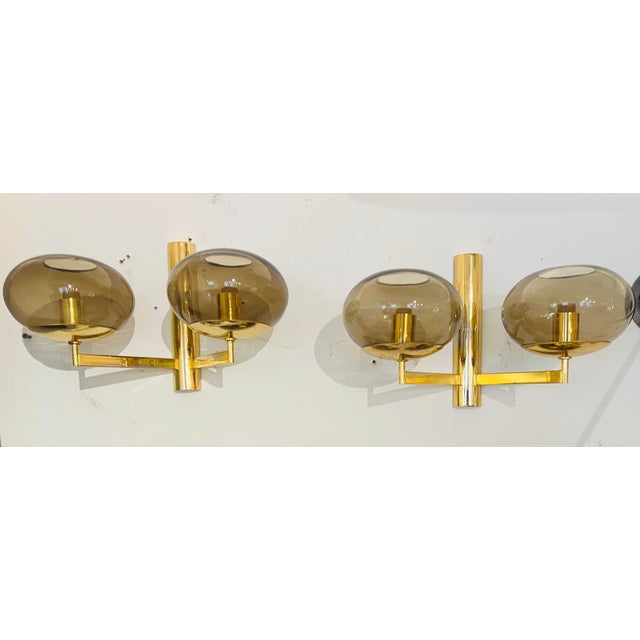 A pair of golden brass double light wall lamps with smoked glass globe shades by the famed Italian lamp maker, Sciolari....