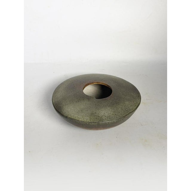 A spherical stoneware vase, made in France in the 1960s, with a circular shape and a central opening, evoking a doughnut-...