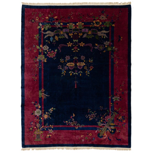 This elegant antique Art Deco Chinese wool rug features a navy blue color field with a decorative border in red and...