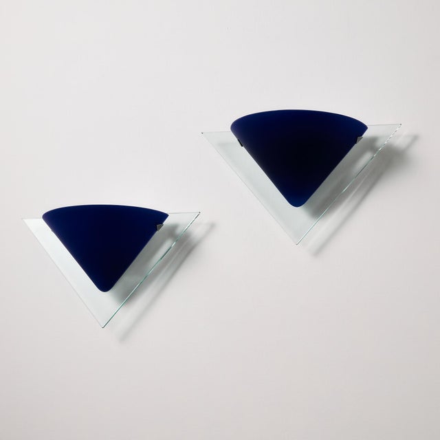 A true Italian postmodern piece from the 1980s. Set of two wall fixtures with blue glass shades, produced by Vistosi. with...