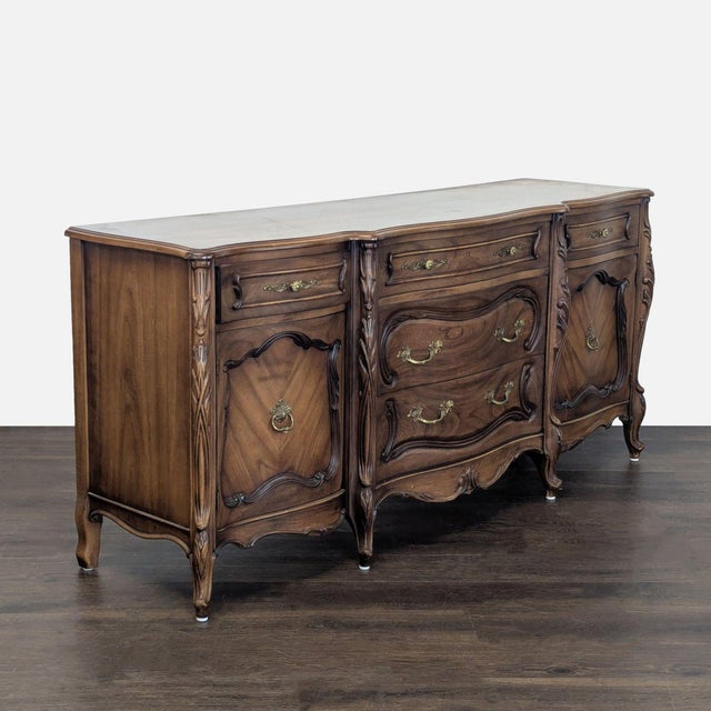 This vintage French Provincial sideboard features beautiful wood grain and ornate brass handles. It offers ample storage...