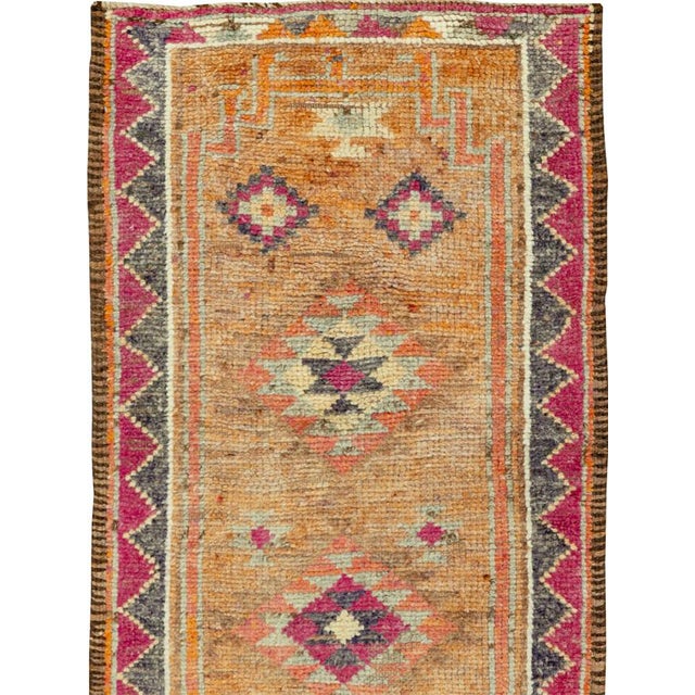 This mid-20th-century Turkish Anatolian runner presents a lively procession of geometric medallions arranged along a warm...