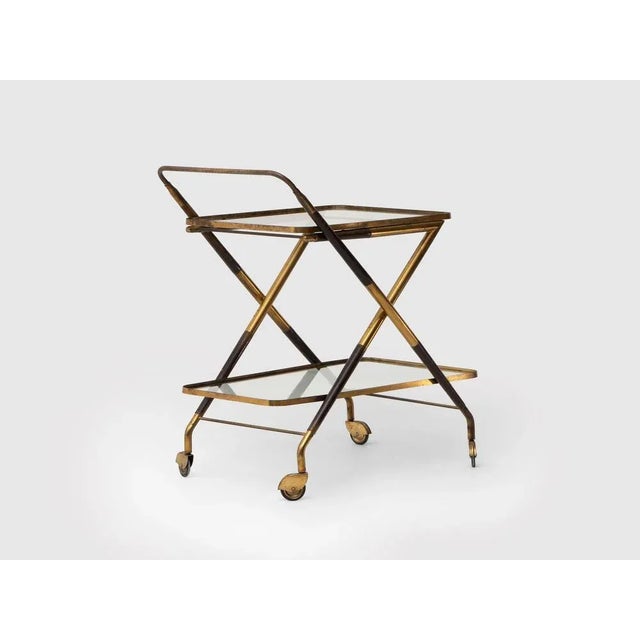 The Italian bar trolley attributed to Cesare Lacca in the 1950s. It is made of glass, brass and lacquered wood. The brass...