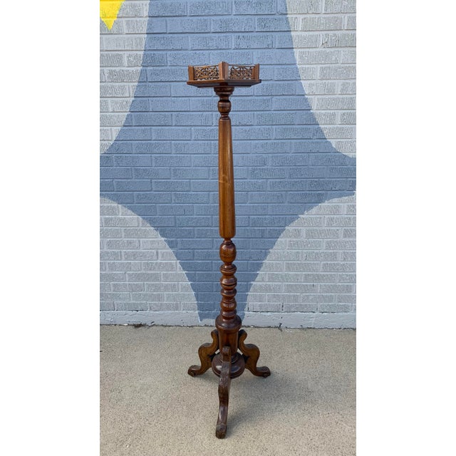 Hexagonal plant stand on a fluted column. Three legs with a carved floral design hold up the pillar. Carved wood detailing...
