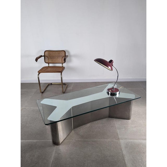 Spectacular coffee table with a fantastic double ypsilon design made of stainless steel and glass with central mirror that...