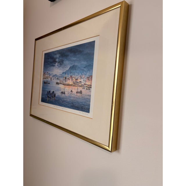 A beautifully atmospheric signed limited edition print depicting a nighttime harbor cityscape with boats and illuminated...