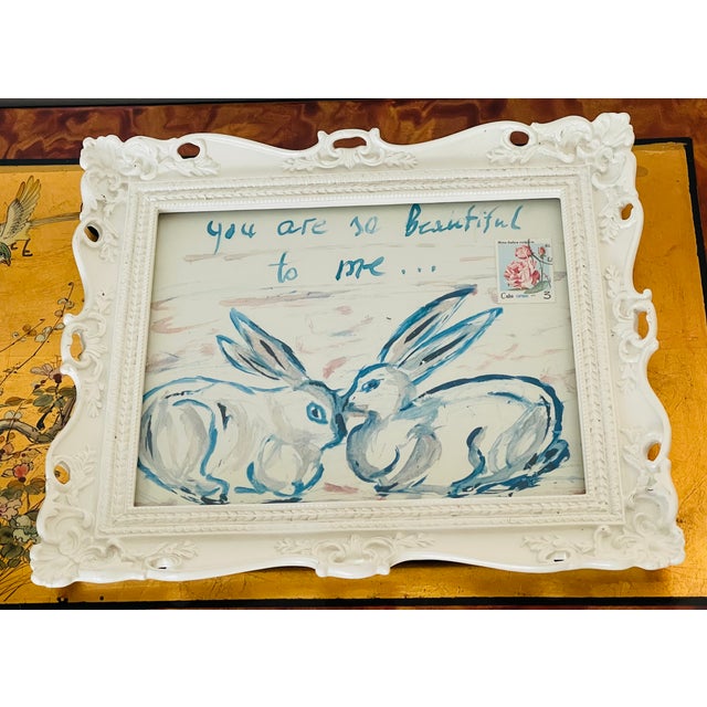 Romantic Rabbits- mixed media collage on canvas from the Ammon Rabbits by Elia, framed in a white ornate frame under glass.