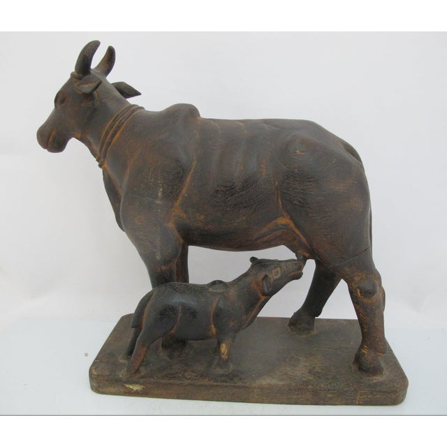 Vintage Indian folk art hand carved wooden statue representing a cow nursing her calf, an iconic depiction of Kamadhenu,...