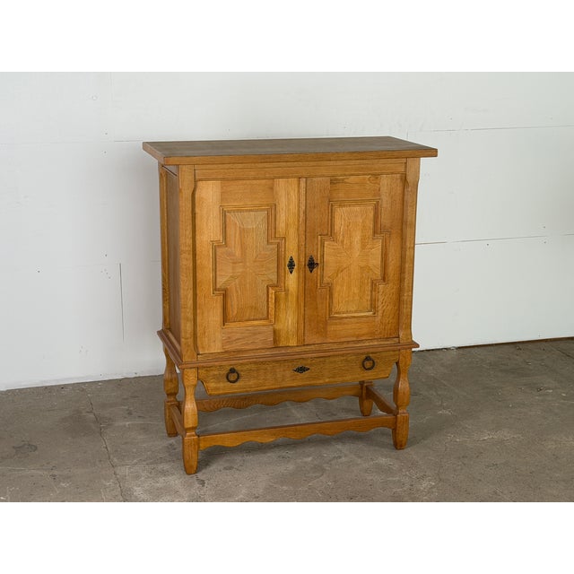 A solid oak two-door cabinet by henning kjærnulf, denmark, 1960s. The door fronts carry kjærnulf's signature geometric...
