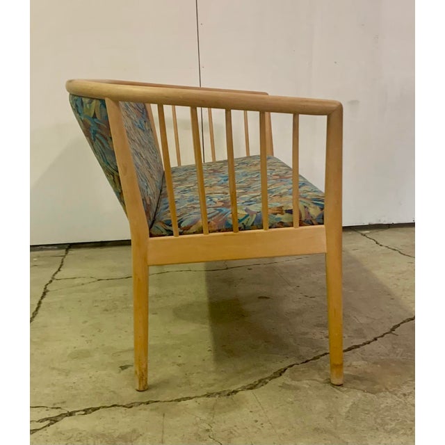 This is a mid-century modern solid wood spindle back loveseat, possibly Swedish, with a botanical print upholstery.