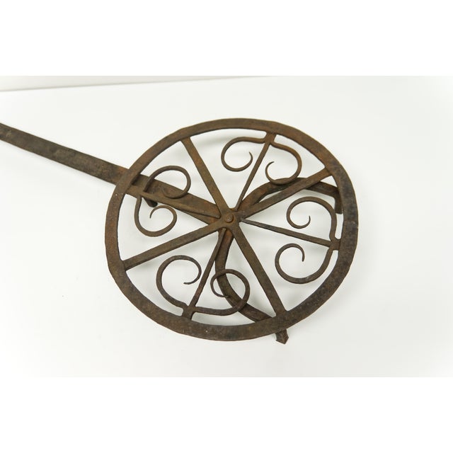 A late 18th century hand forged iron fireplace rotating trivet featuring decorative scrolls. Original condition.