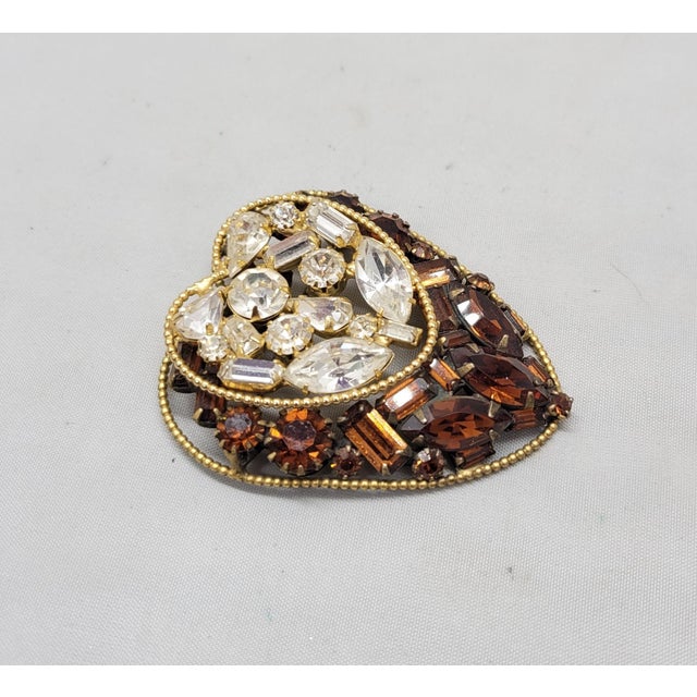 1950s goldtone prong set baguette, round and pear shaped clear and faux-topaz rhinestones heart shaped brooch with...