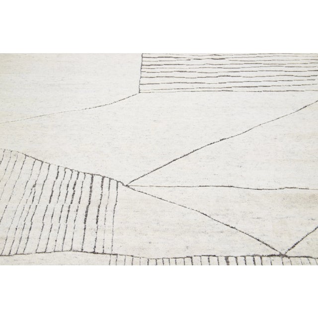 This luxurious wool rug features a timeless Moroccan pattern in a contemporary abstract Minimalist style, utilizing Ivory...