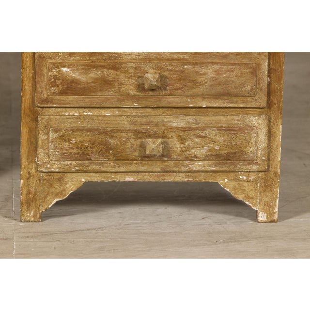 A near pair of vintage bedside chests with six drawers and distressed patina. A harmonious blend of rustic charm and...