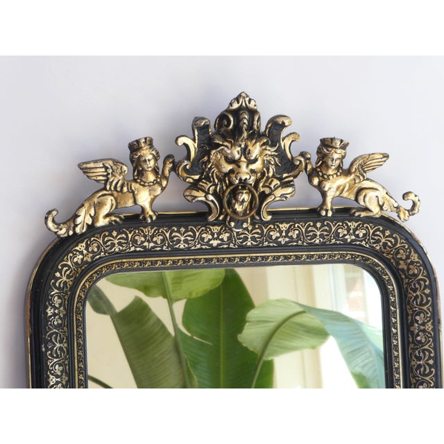A stunning long antique Louis Philippe wall mirror with an ornate black and gold arched frame. On the top you will find...