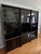 - German-made by Schieder Möbel in the 1980s - Black lacquer finish with glass doors and gold/brass accent hardware -...