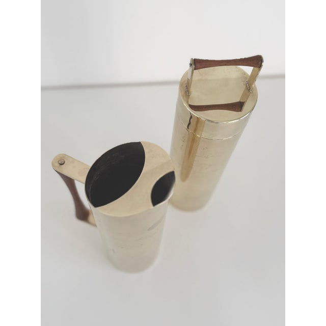 Cylindrical cocktail mixer and pitcher set, made in Italy circa 1950s. Made of brass-plated stainless steel with turned...