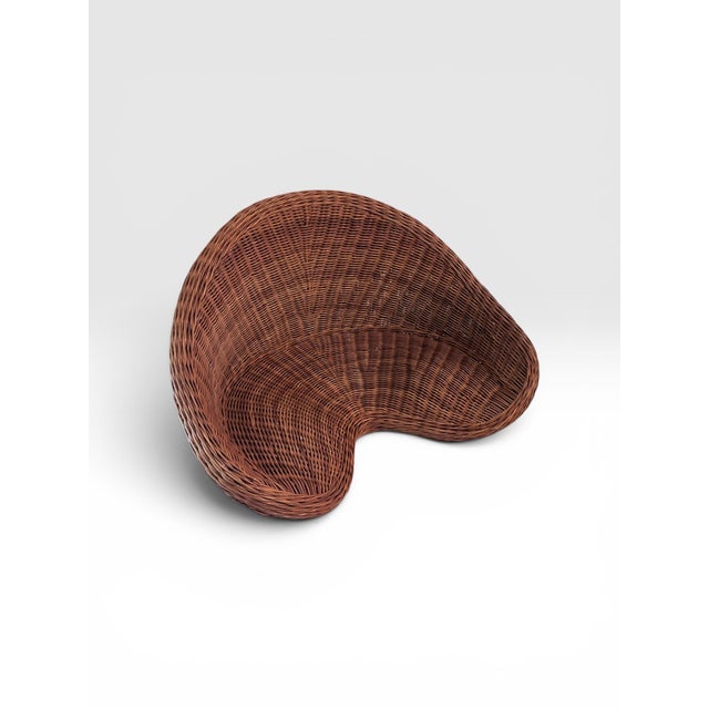 An exceptional vintage handwoven rattan floor chair featuring a graceful crescent silhouette designed for relaxed...