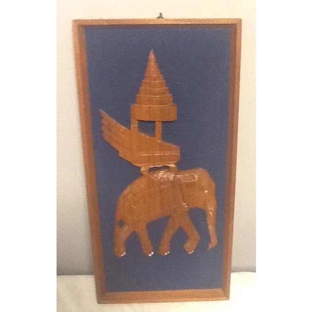These mirror image vintage elephant carvings are set on a royal blue corduroy fabric background in a simple wood frame....