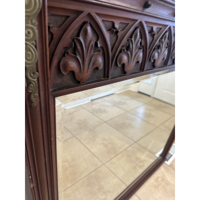 A striking statement piece, this grand wall mirror features an architectural frame with intricate Gothic tracery and...