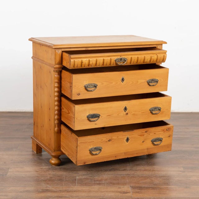 Antique pine chest of four drawers resting on bun feet. Traditional half column detail, simple carved top drawer, dove-...