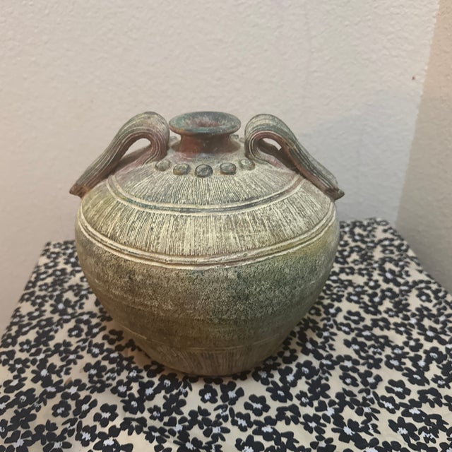 A striking vintage pottery jar that captures the rugged elegance of ancient East Asian ceramics. This piece features a...