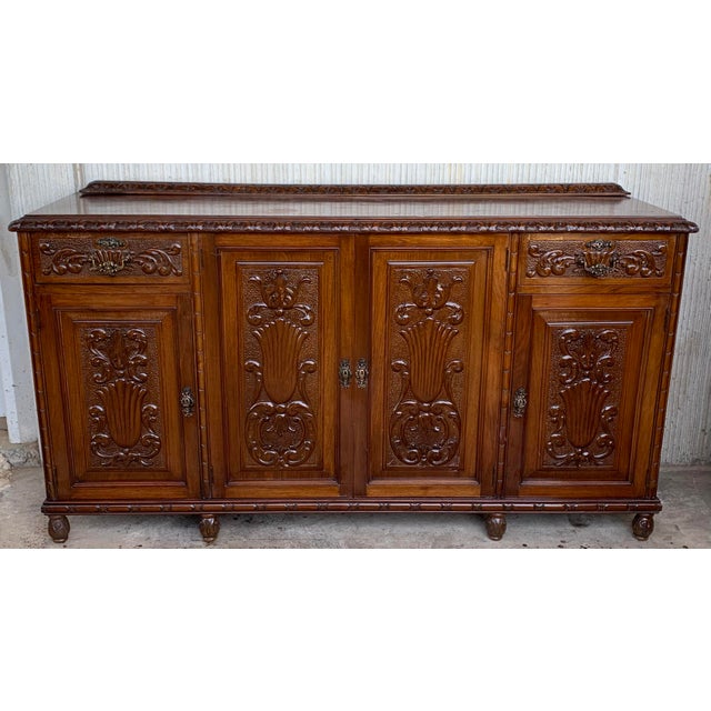 Early 20th carved walnut sideboard with four doors and two drawers Elaborate carved walnut sideboard from Spain is topped...