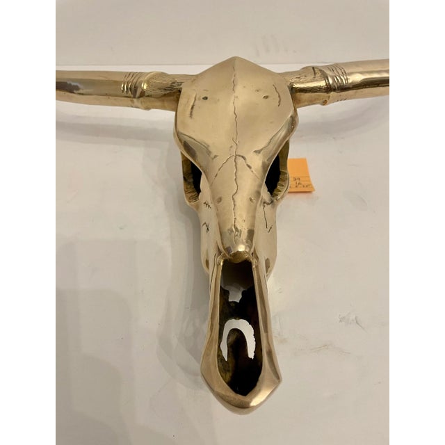 Circa mid-20th century Hollywood Regency style decorative brass longhorn skull wall sculpture in a hand polished finish....