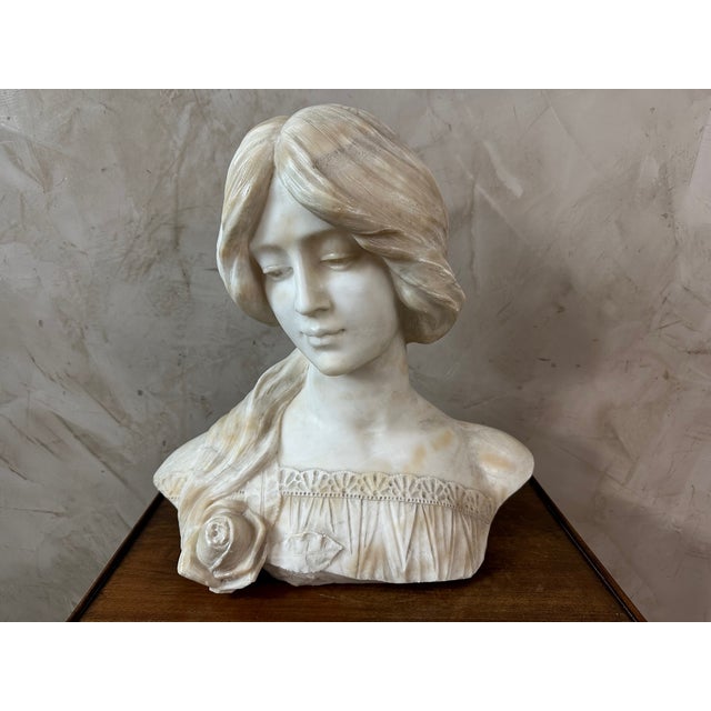 A superb sculpted marble bust depicting a young woman with delicate features, typical of the art nouveau aesthetic. Her...