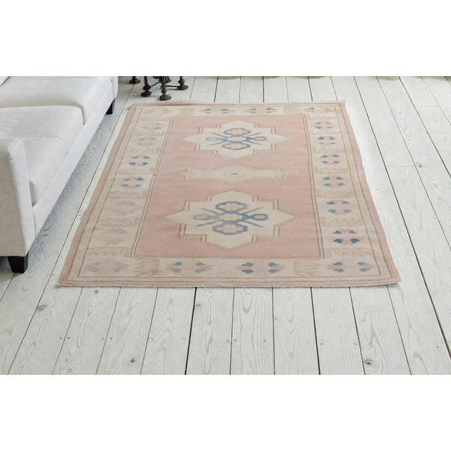 This is a vintage Turkish Oushak rug from the Mid 20th Century. The piece was hand-knotted.