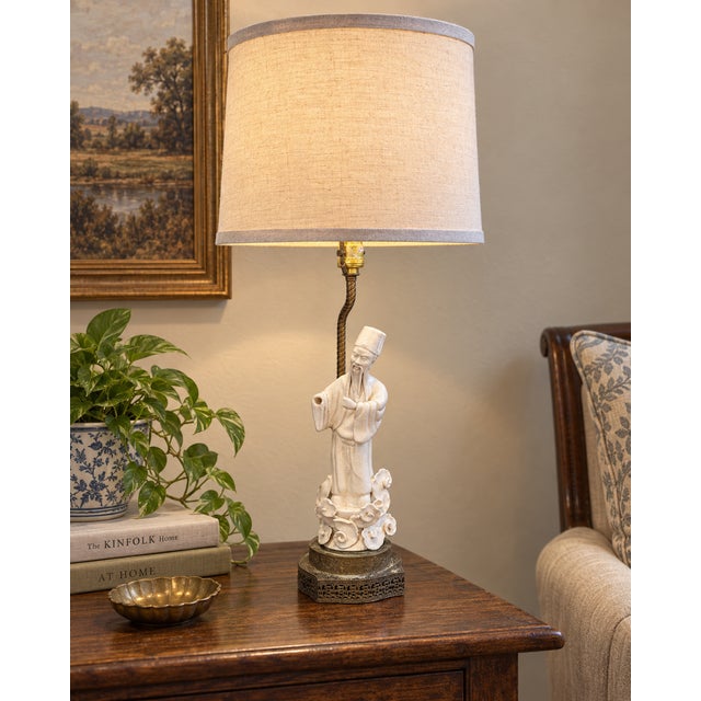 A distinctive vintage Chinese porcelain figural table lamp depicting a traditionally robed scholar or immortal in a creamy...