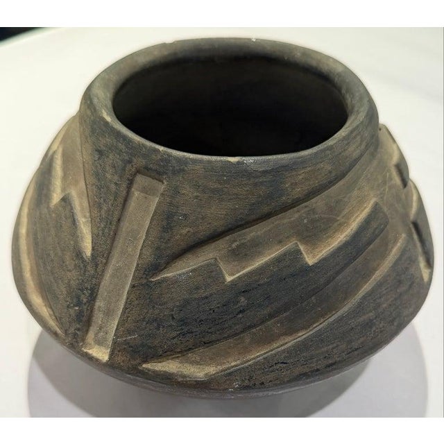 This hand-coiled Native American Santa Clara Pueblo, NM pottery vessel features a dark gunmetal finish with carved...