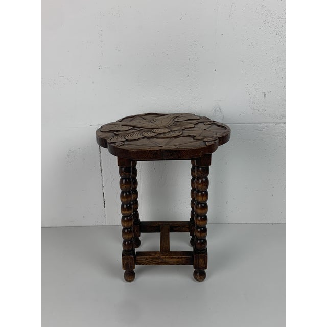 A small occasional table in solid oak, quatrefoil scalloped top hand-carved in deep relief with a lotus design — leaves,...