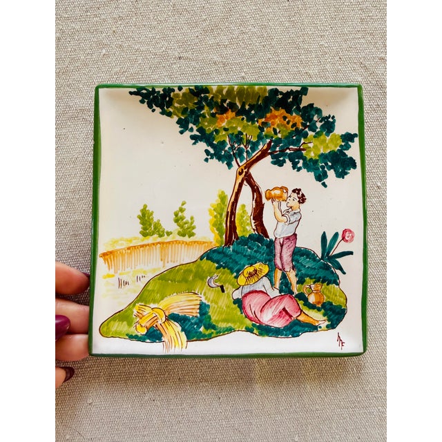 A charming hand-painted Italian ceramic wall plate depicting a warm summer countryside scene, featuring harvest imagery...