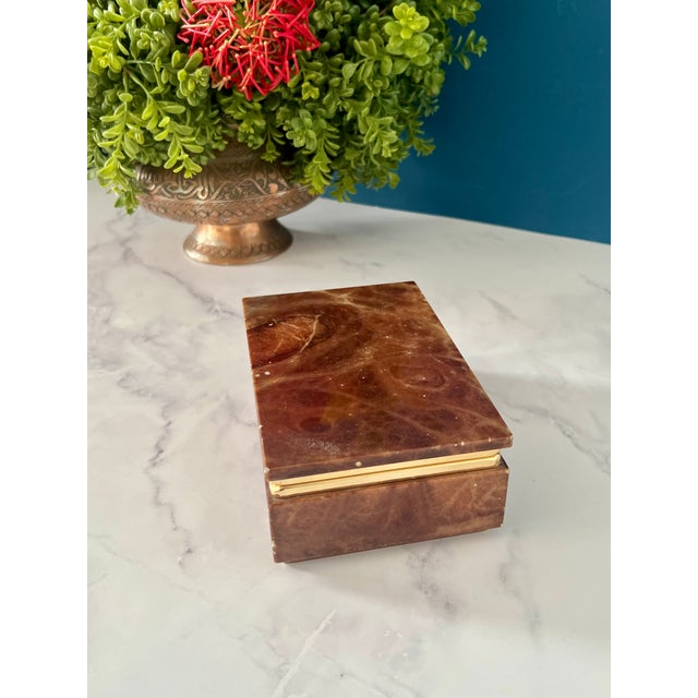 A beautiful vintage red alabaster jewelry box finished with elegant brass detailing, showcasing dramatic natural stone...