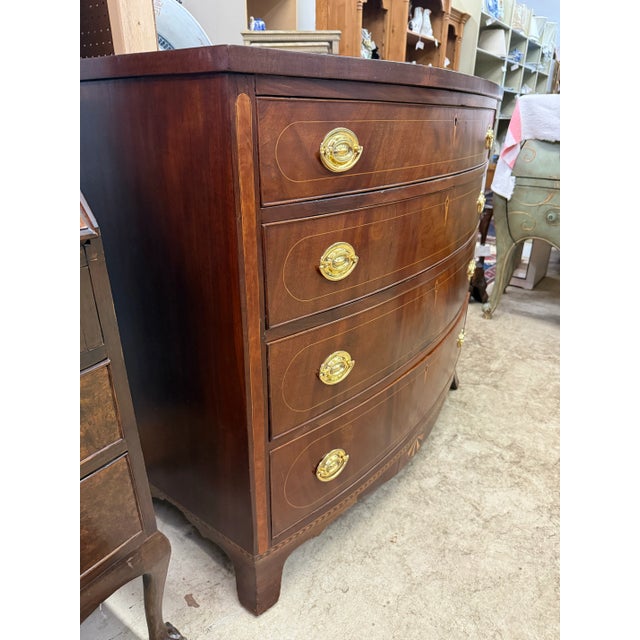 Handsome American bow front four drawer inlaid graduated chest with French splay foot. Brasses are probably replaced.