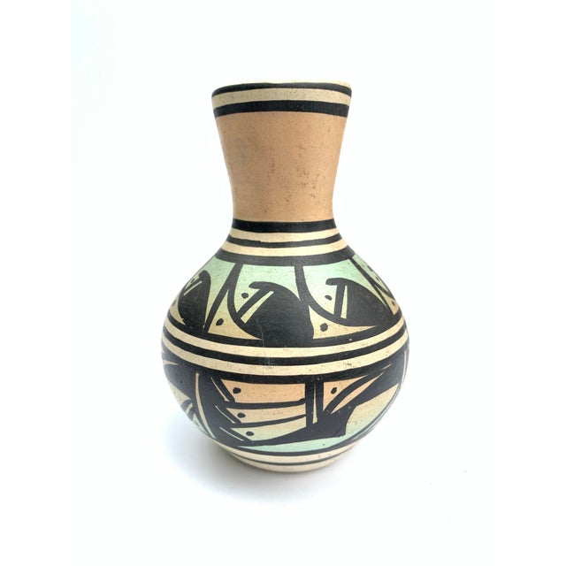 A petite vintage Navajo clay pot with soft pink and blue painted decoration. The pot is signed on the bottom.