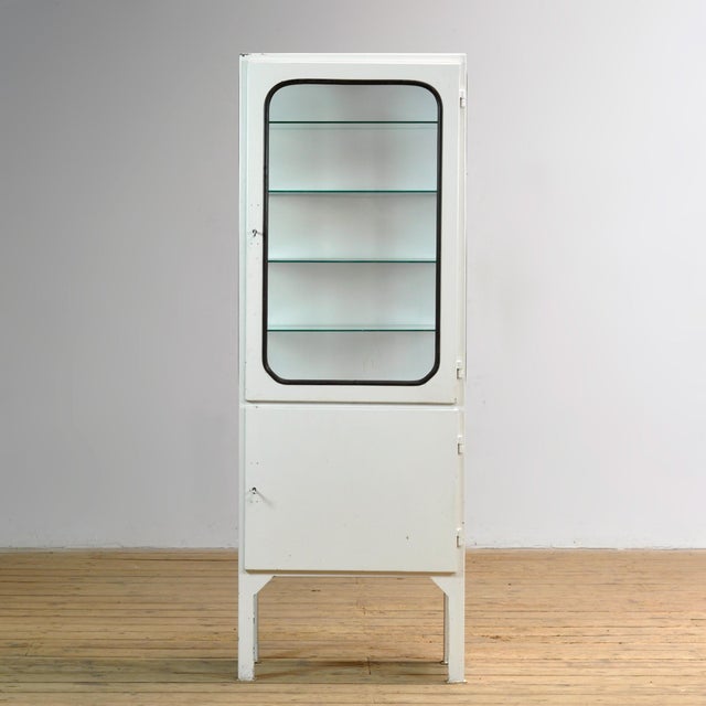 Vintage medicine cabinet from the 1970s, produced in Hungary. This cabinet is made of iron and glass, with the glass held...