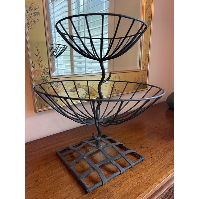 Vintage sculptural two-tier fruit stand or centerpiece basket crafted in hand-forged iron. The organic vine-form stem,...