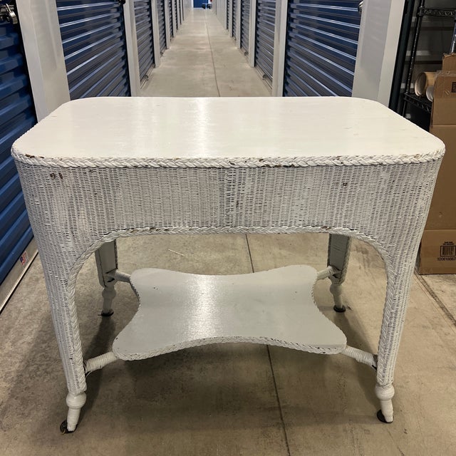 A chic antique wicker library table offering timeless appeal. Its intricate woven design and white finish create a...