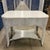 A chic antique wicker library table offering timeless appeal. Its intricate woven design and white finish create a...