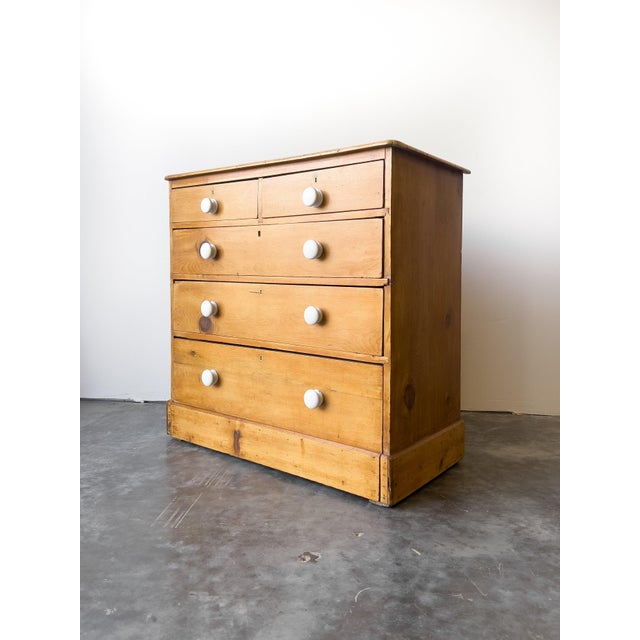 A beautiful 19th-century English pine chest featuring a warm, waxed finish, with crisp white porcelain knobs. This piece...