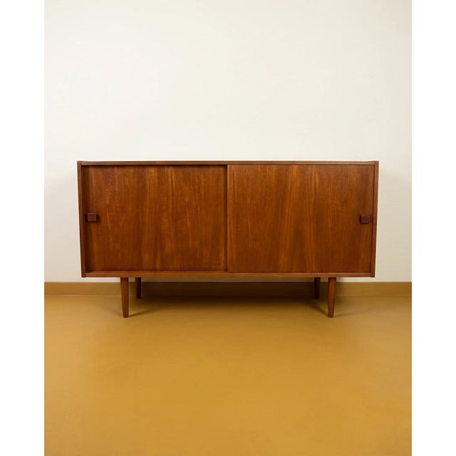 A small danish teak sideboard with two sliding doors and square teak button handles—a detail that reveals its quality...