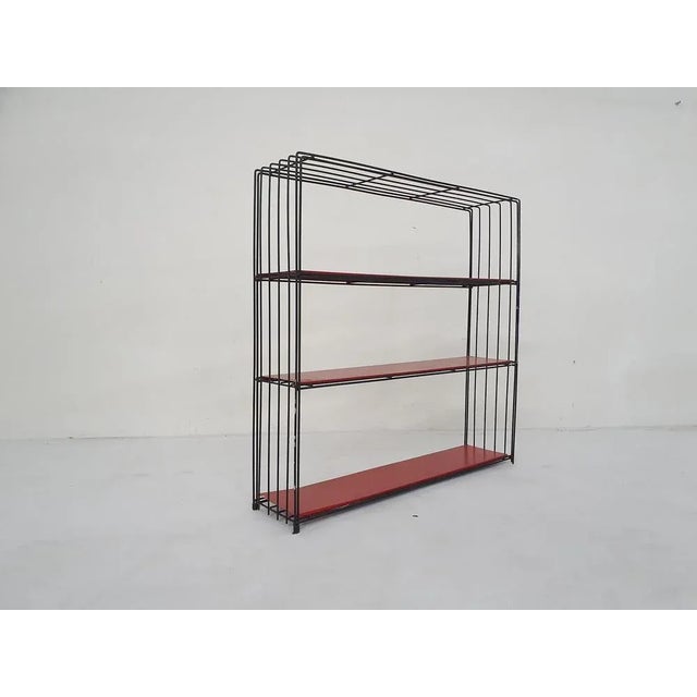 Minimalistic black metal wired book case with 3 metal red shelves. In good original condition Tjerk Reijenga This piece is...