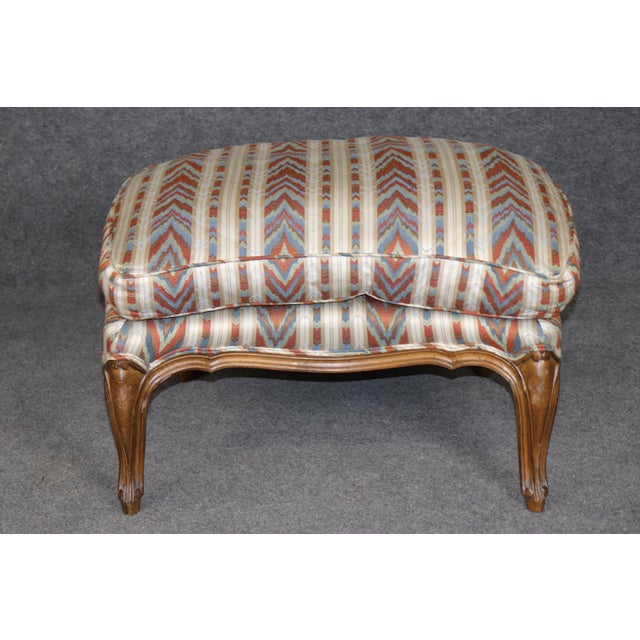 This handsome French Louis XV-style walnut bergère with matching ottoman, dating to approximately the 1950s, is an...