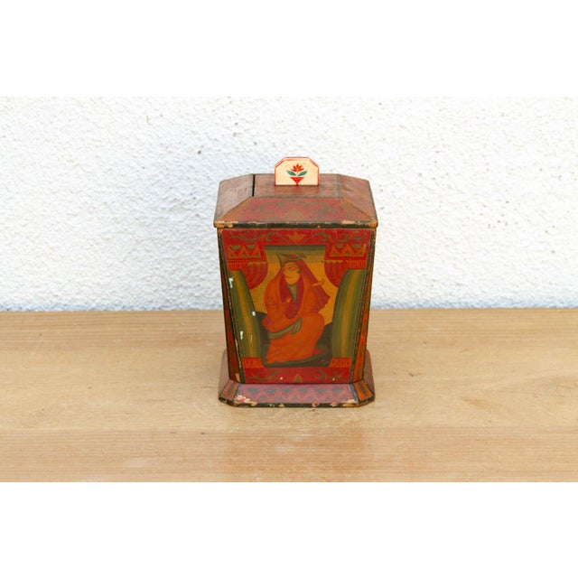 This solid wood caddy is an authentic piece of Kashmiri artisan craft, notable for its rich, saturated palette of madder...