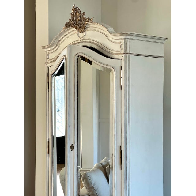 A refined example of 19th century French provincial craftsmanship, this Louis XV–style armoire features an elegant bonnet...