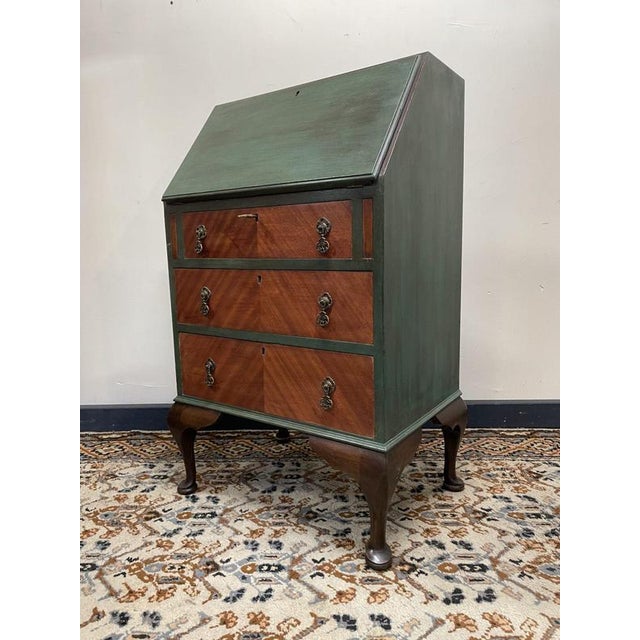 A vintage Queen Anne–style fall-front writing bureau, finished in dark green with exposed natural wood to the drawers and...