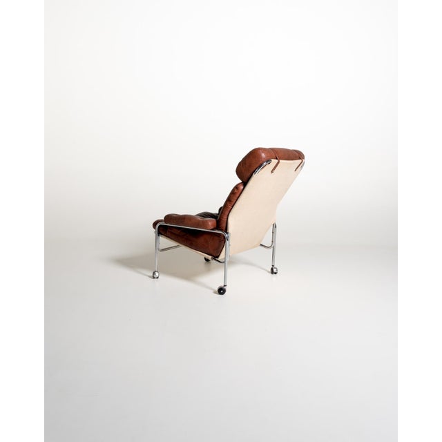 Swedish armchair from the 1960s/1970s with a chromed tubular steel frame and brown leather upholstery. The seat and back...