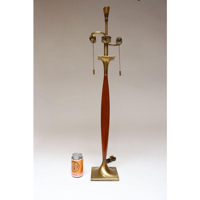 Statuesque Laurel table lamp composed of an elongated and slim elliptical walnut stem with polished brass rectangular base...